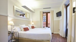 A hotel room with a bed, bedside lamps, a bedside table with a phone, a TV mounted on the wall, and a balcony with curtains. - U-Sense Sevilla Centro (Seville)