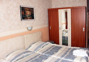 Une chambre à coucher avec un lit, une armoire, un tableau et une table de chevet.
