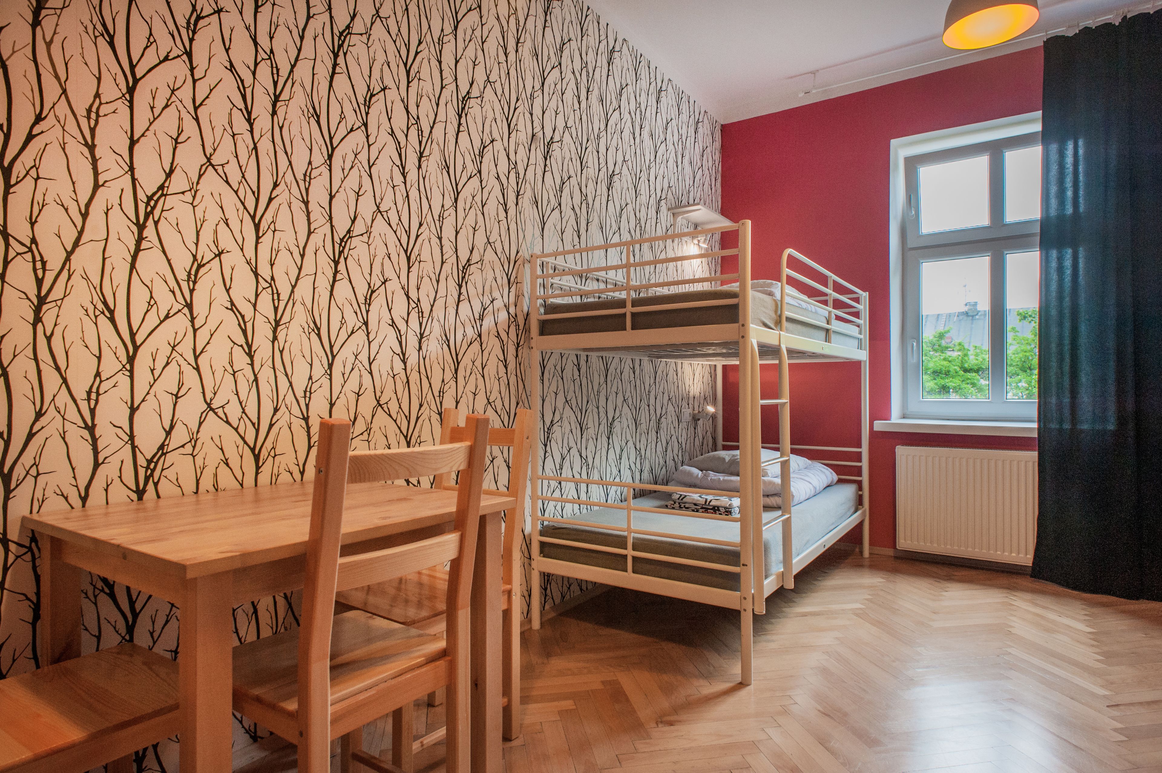 Ein Zimmer mit einem Etagenbett, einem Holztisch und einem Stuhl.