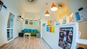 A modern interior with a green sofa, white table, and orange pendant lights. - Hostel Atlantis (Kraków)