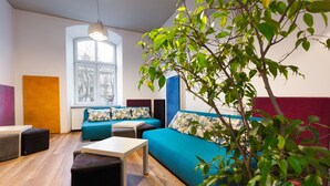 A modern living room with a blue sofa, a white table, and a plant. - Hostel Atlantis (Kraków)