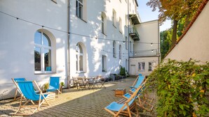 A courtyard with outdoor seating, a potted plant, and a building with multiple windows and balconies. - Hostel Atlantis (Kraków)