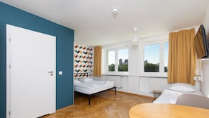 A room with a bed, a table, a window, and a door. - Hostel Atlantis (Kraków)
