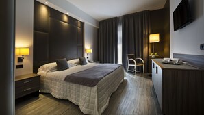 Une chambre d’hôtel moderne avec un grand lit, des lampes de chevet, un bureau et une télévision.