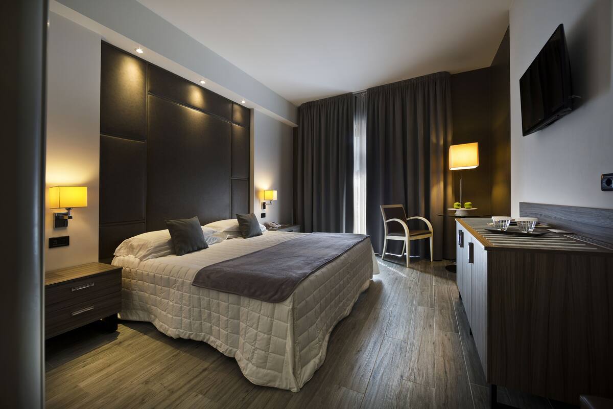 Une chambre d’hôtel moderne avec un grand lit, des lampes de chevet, un bureau et une télévision.