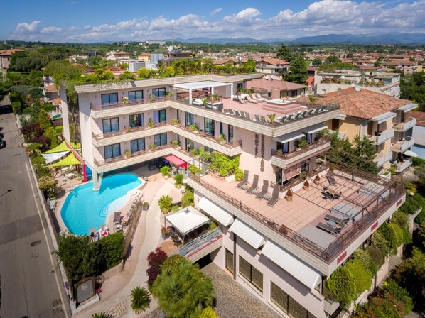 A modern hotel with a rooftop pool, multiple balconies, and a view of the surrounding area. - Hotel Desenzano (Desenzano del Garda)