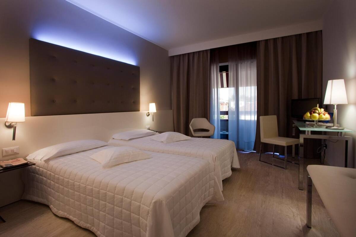 Une chambre d’hôtel avec deux lits, un bureau, une chaise et un téléviseur.