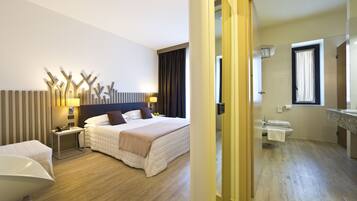 Habitación de hotel con cama, mesitas de noche, un espejo y un baño con lavabo e inodoro.