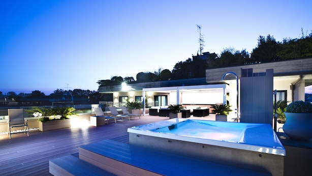 Un espace piscine aménagé sur le toit, comprenant un jacuzzi, des sièges et des plantes en pot.