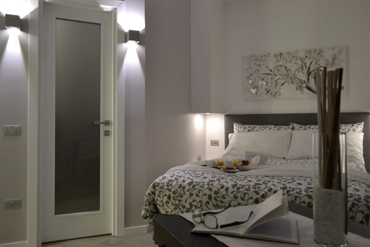 A bedroom with a bed, bedside table, and a door with frosted glass panels.