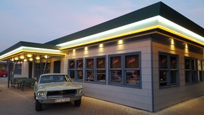 A building with a modern design, featuring a flat roof and a series of windows with neon signage. - Wittrup Motel (Albertslund)
