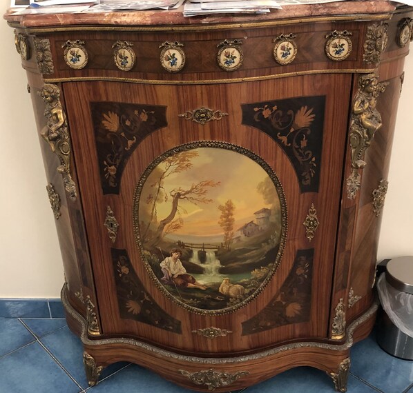 A wooden cabinet with ornate carvings and a central oval painting depicting a pastoral scene. - Meublè Casa Mannini (Maiori)