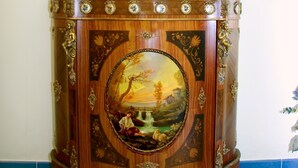 Ein Holzschrank mit Spiegel, eine Vase mit Pflanze und ein gerahmtes Bild.
