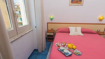 A hotel room with a bed, breakfast tray, and a view of the outside.