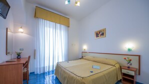 Ein Hotelzimmer mit Bett, Schreibtisch, Stuhl, Nachttisch und Spiegel.