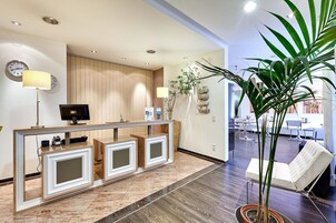Zona de recepción con un mostrador de madera, un reloj y una planta en maceta.
