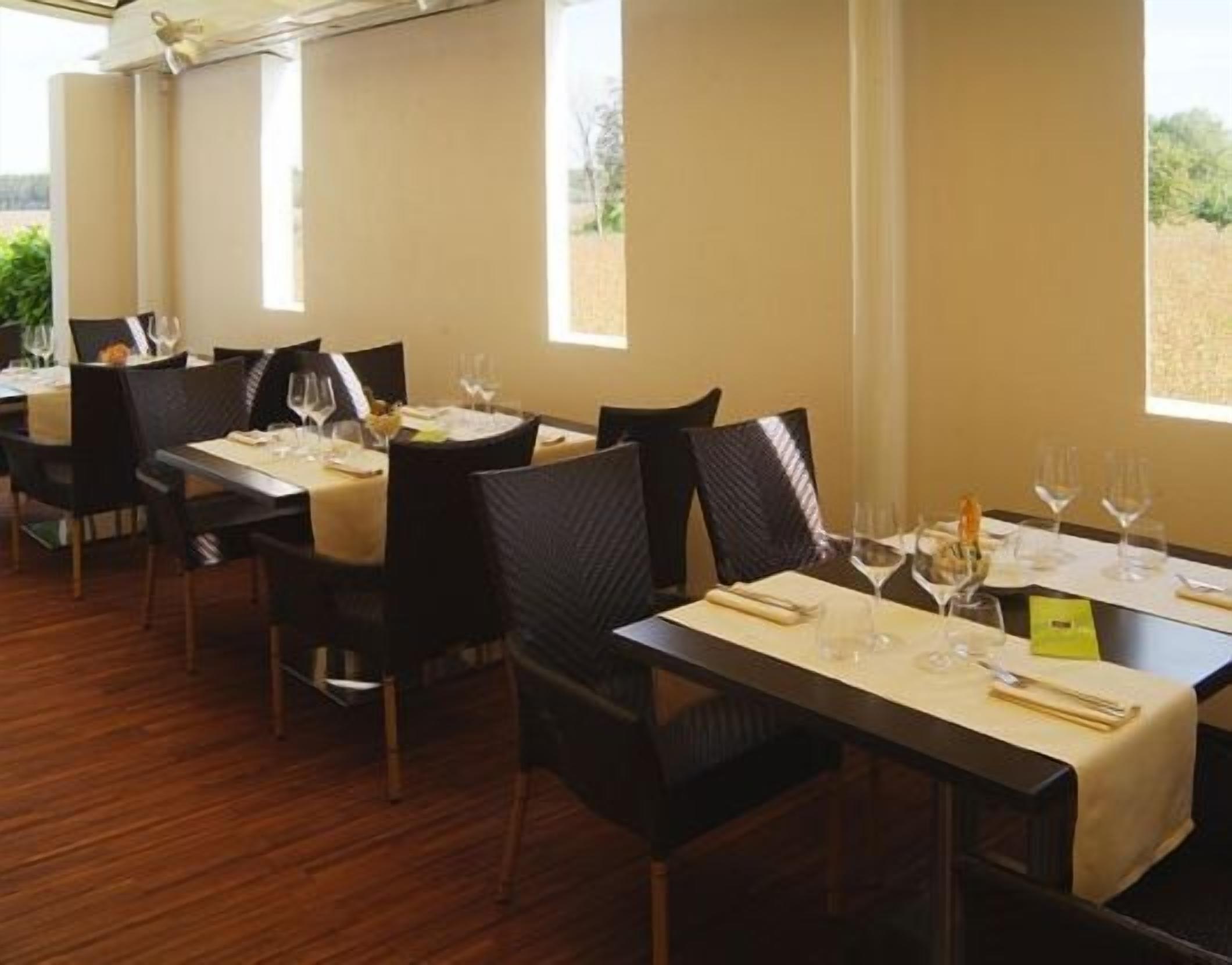 A restaurant with tables set for dining, chairs, and wine glasses.