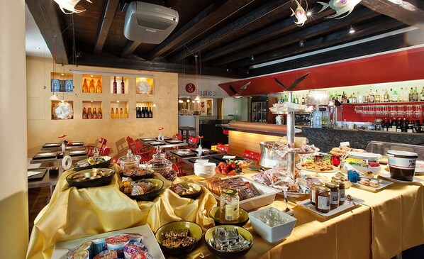 A buffet setup with various food items and condiments. - Hotel Il Cecchini (Pasiano di Pordenone)