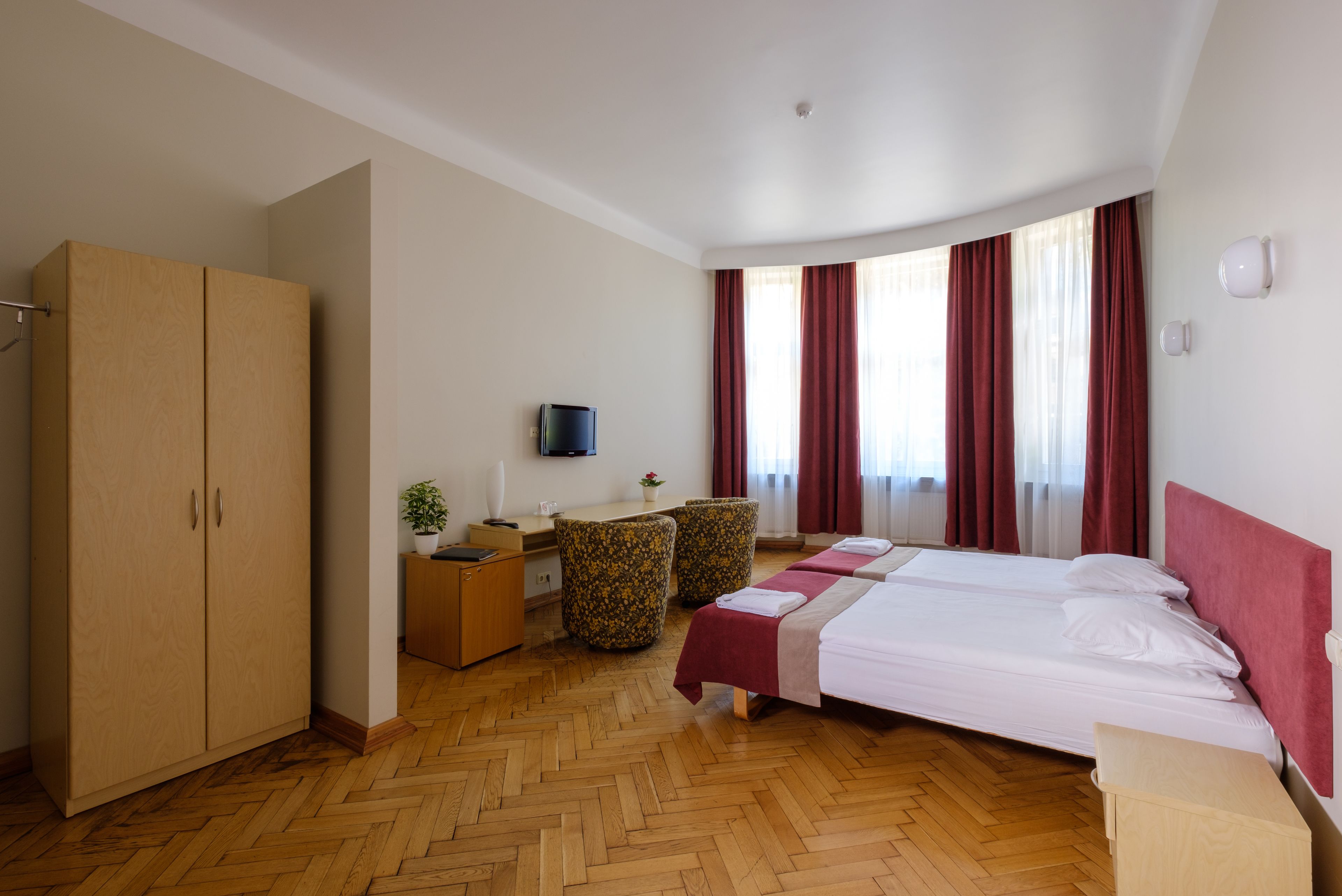 Una habitación de hotel con dos camas, un escritorio, un televisor y un armario.