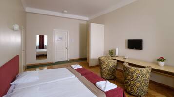 Une chambre d’hôtel avec deux lits, un bureau, une chaise, une télévision et une petite plante.