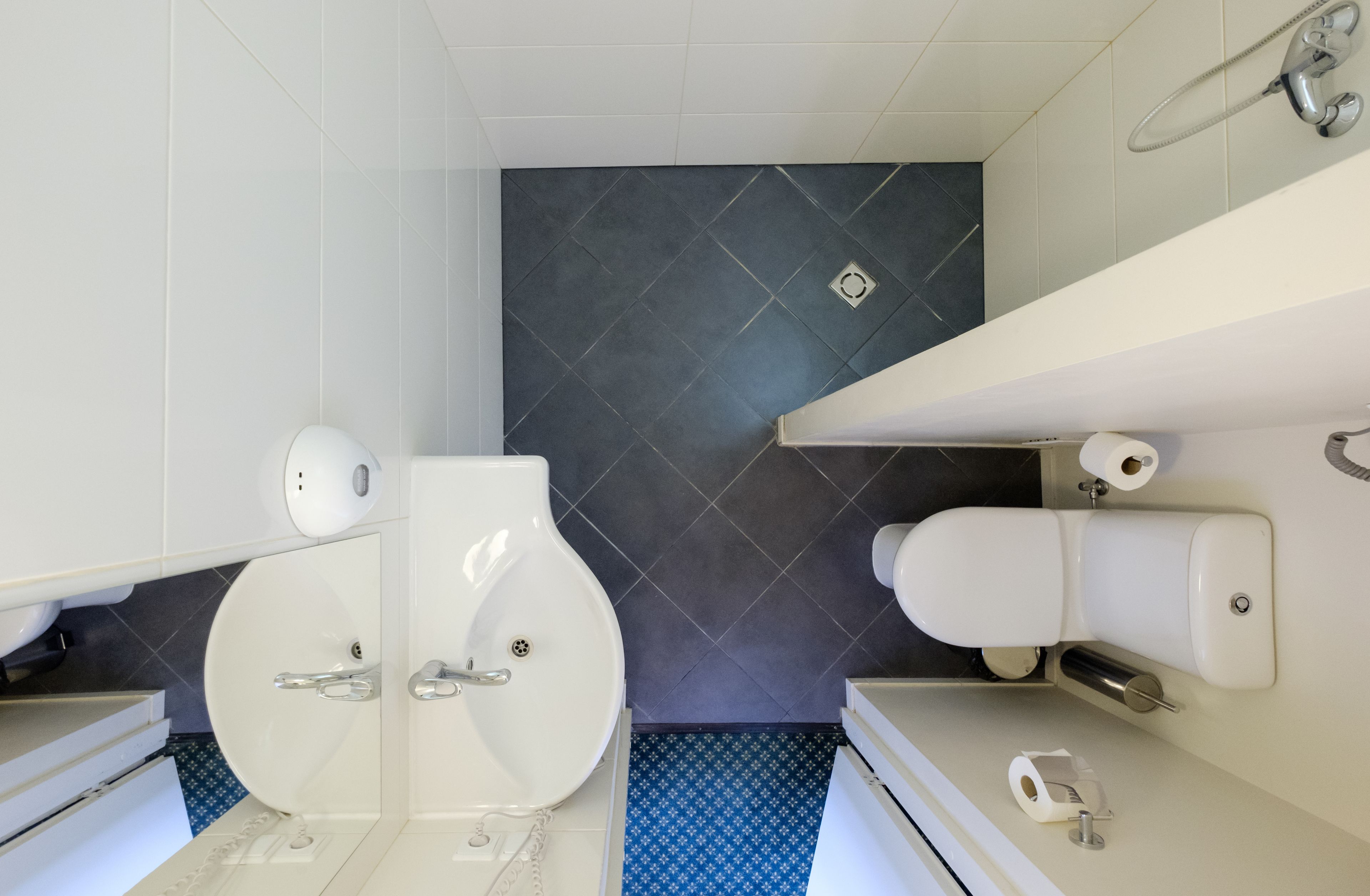 A modern bathroom with two toilets, a shower, and a sink.