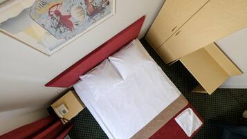 Una habitación con una cama, un teléfono y un cuadro en la pared.