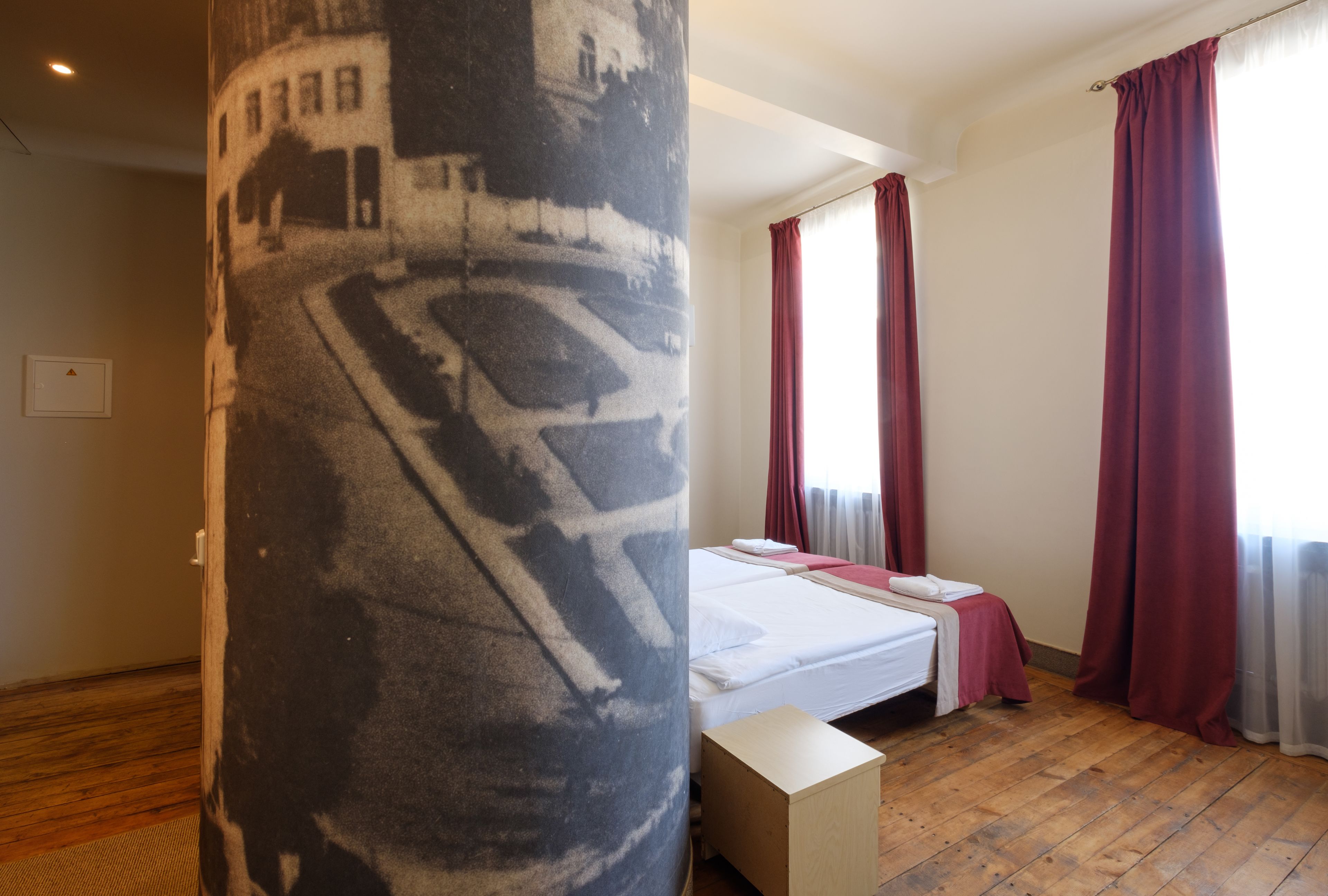 Une chambre à coucher avec un lit, un plancher en bois et une grande colonne ornée d’un motif de carte.