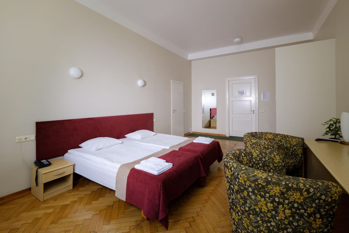 Una habitación de hotel con una cama grande, dos mesitas de noche, una silla y un escritorio.