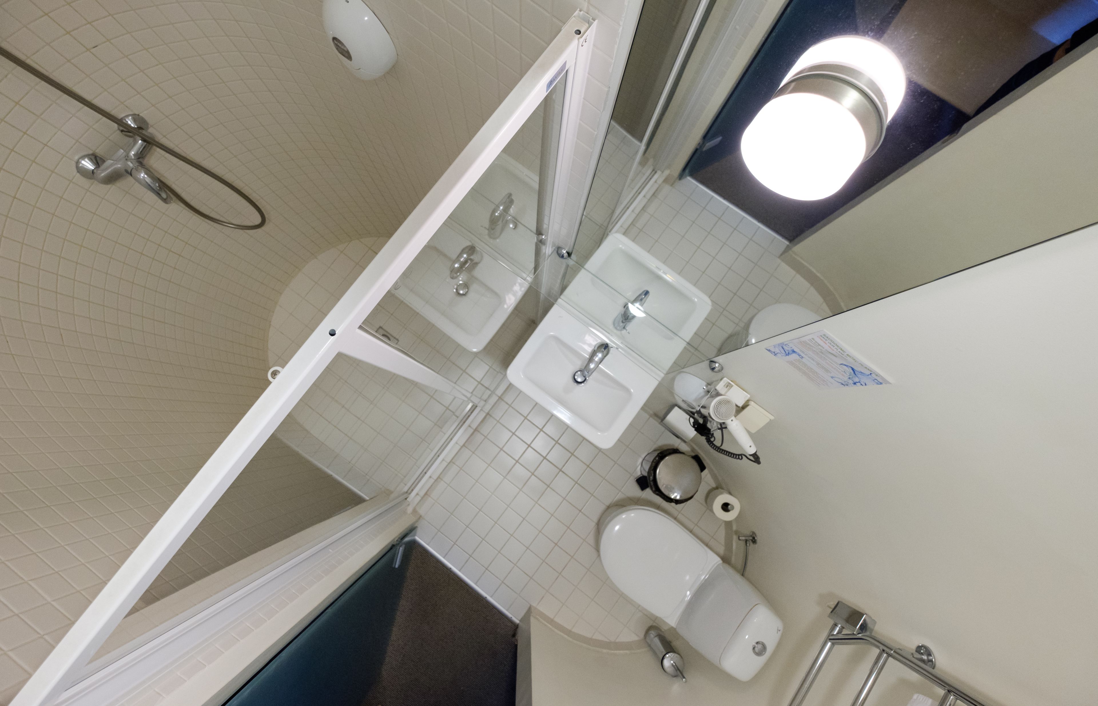 Une salle de bain avec une douche, deux lavabos, des toilettes et un miroir.