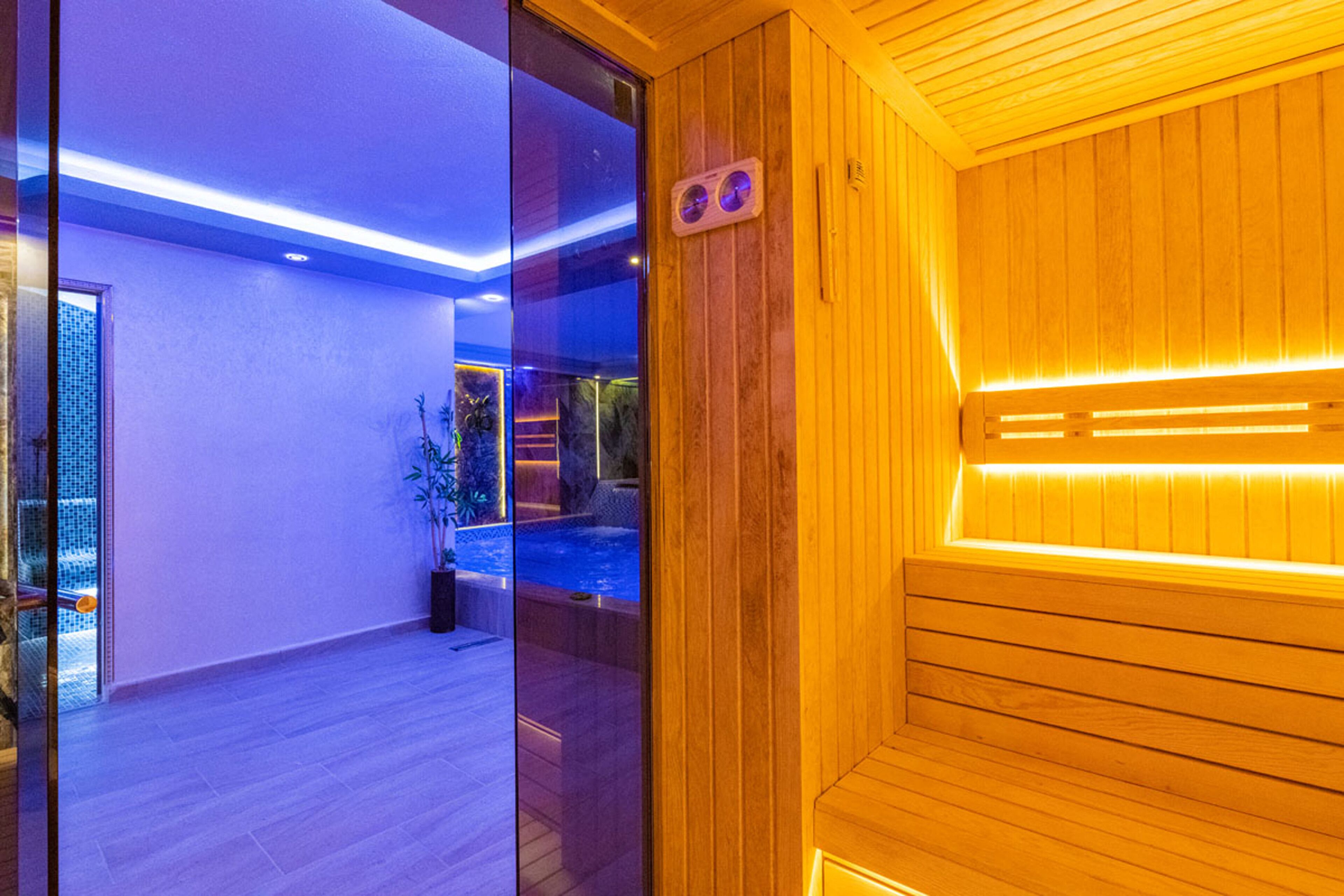 Una sala de sauna con paredes de madera y un ventanal que da a una zona de piscina.