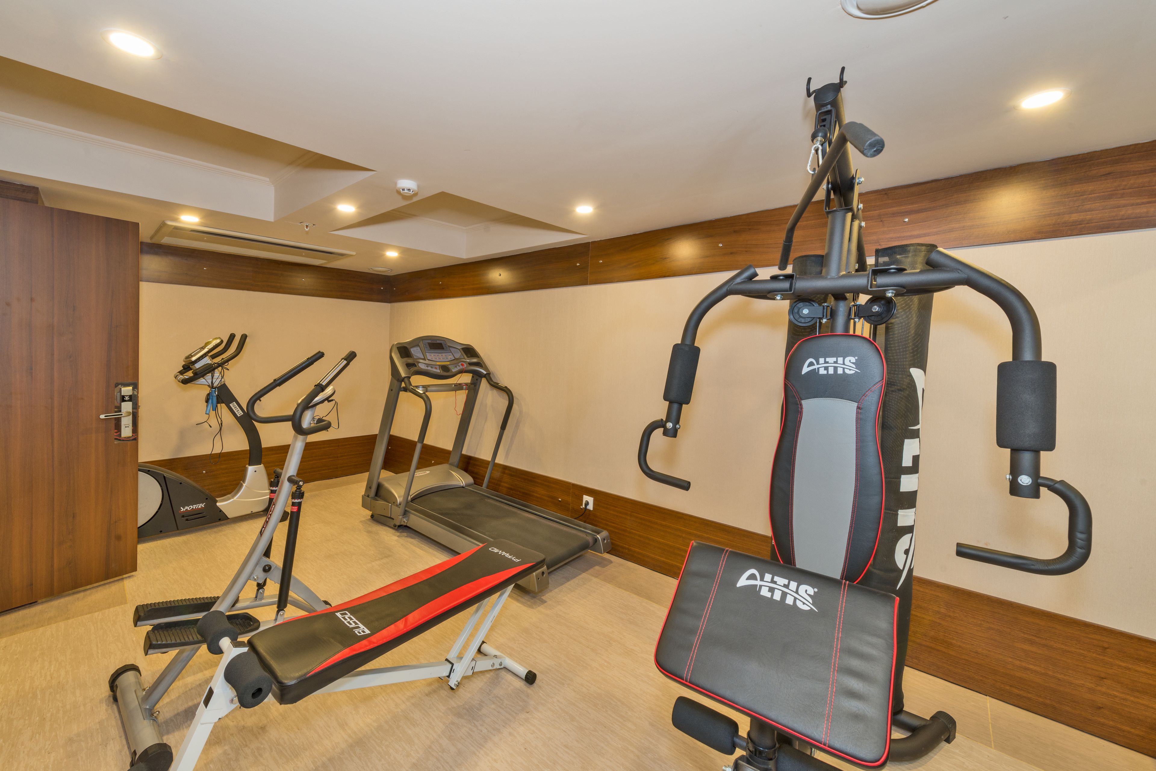 Uma academia com esteiras, bicicleta ergométrica e um banco de musculação.