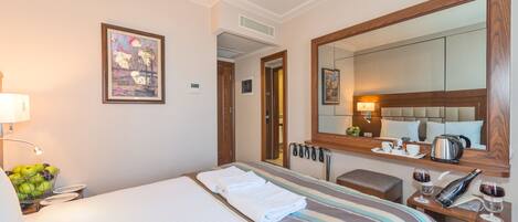 Una habitación de hotel con una cama, una mesita de noche con lámpara, un espejo y un cuadro en la pared.