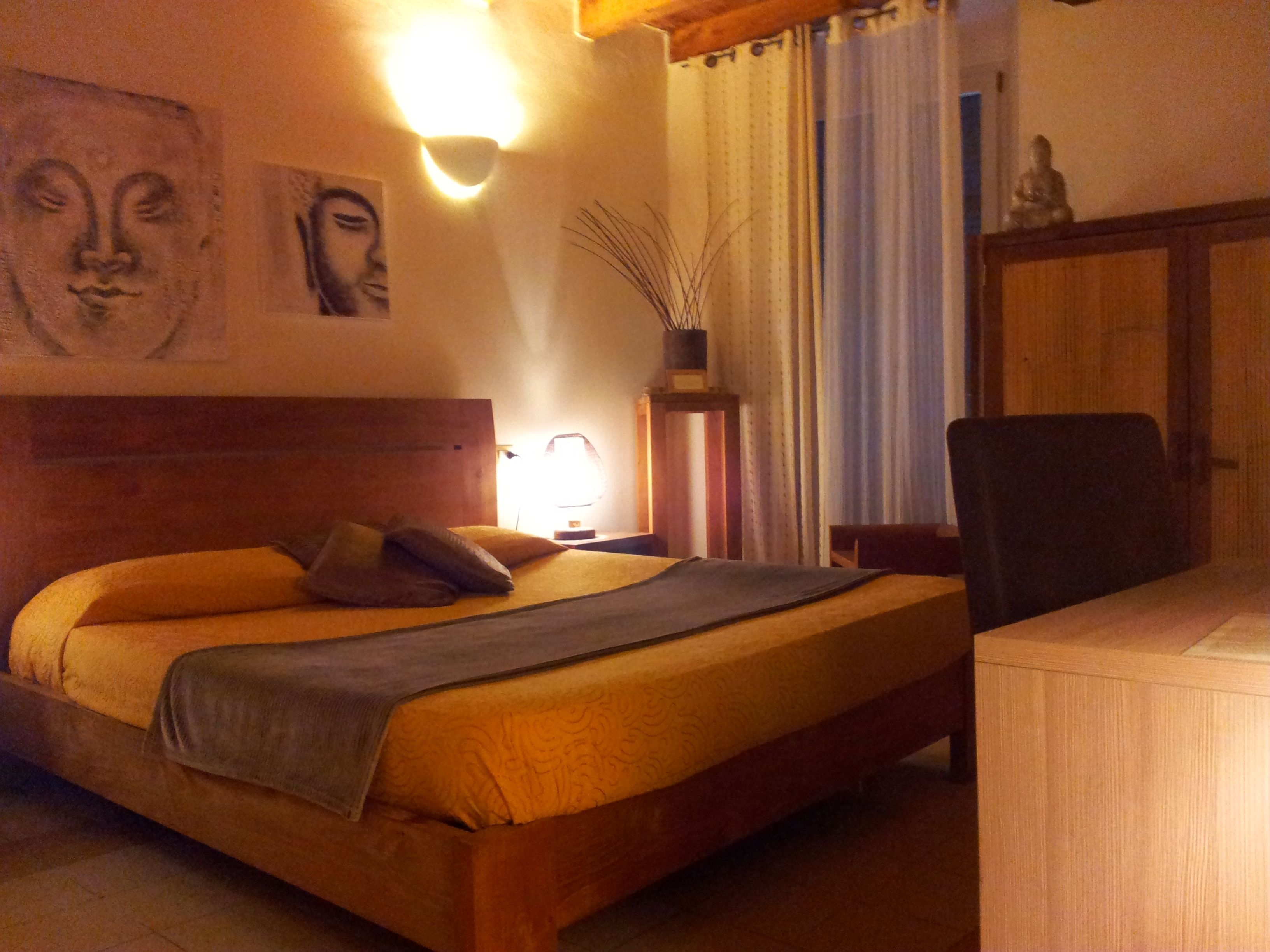 A bedroom with a bed, a nightstand, a lamp, a chair, and a cabinet.