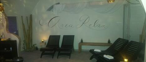 Una habitación con dos sillones, una mesita y una pared con la inscripción 'Orea Relax'.
