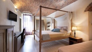 A four-poster bed with a wooden frame, a desk with a chair, a television mounted on the wall, and a bedside table with a lamp. - Hotel Relais al Convento (Vezzano Ligure)