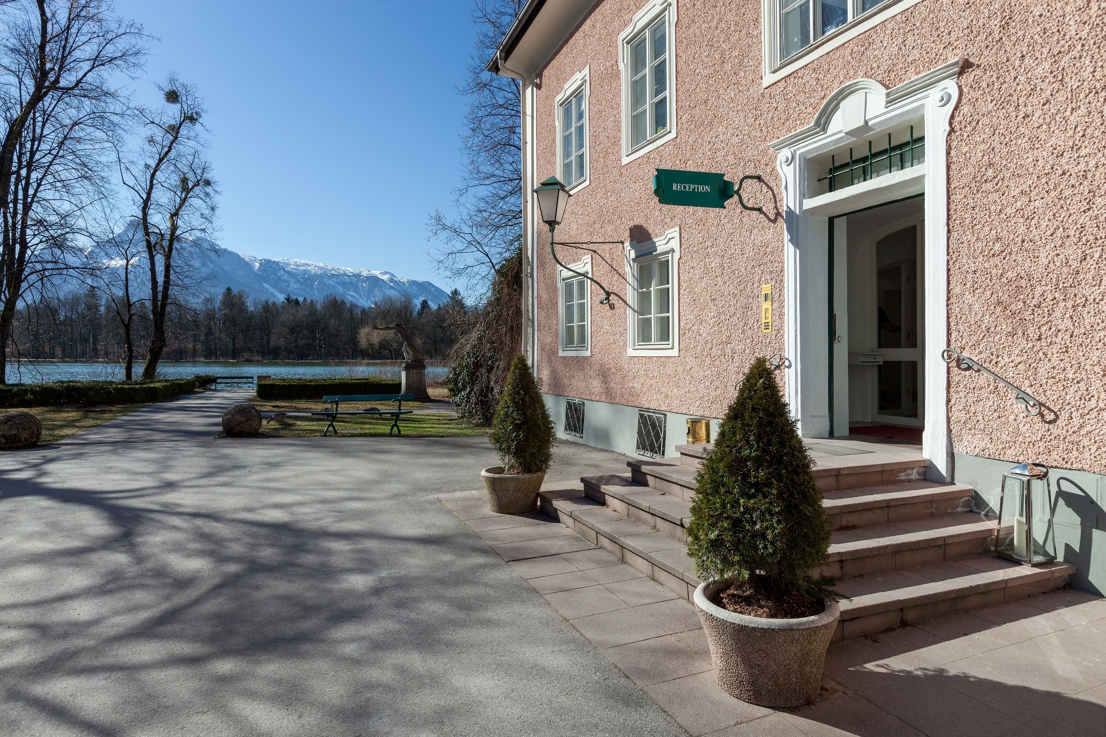 Un edificio con un cartel de recepción, escalones que llevan a una puerta y una vista de un lago y montañas al fondo.