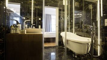 A modern bathroom with a marble floor, a white bathtub, and a glass-enclosed shower area.