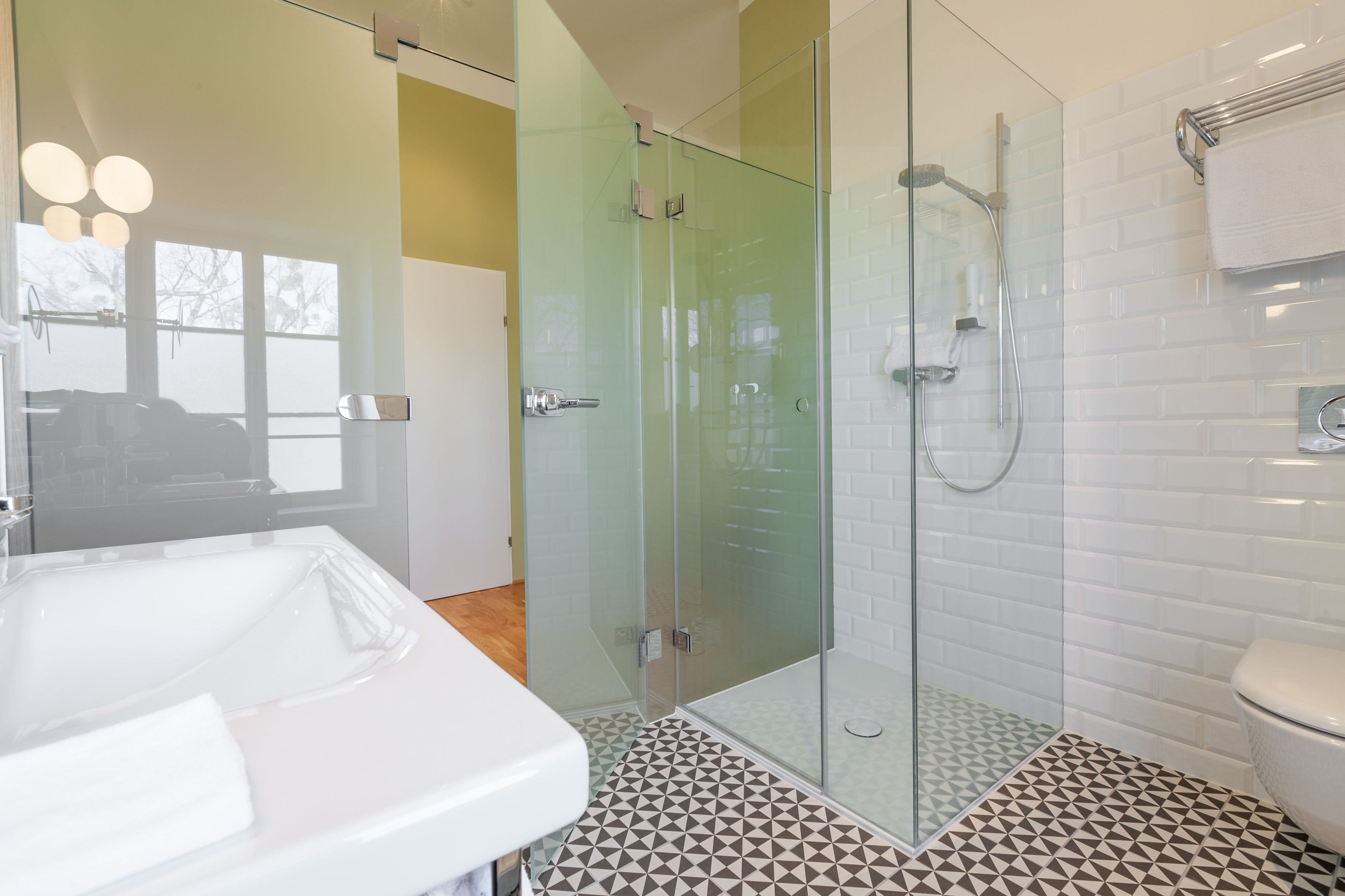 A bathroom with a glass-enclosed shower, a white sink, and a toilet.
