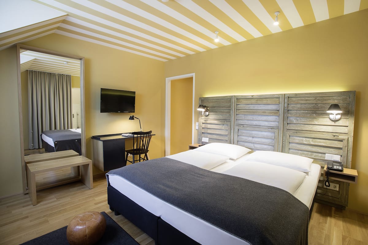 Quarto de hotel moderno com uma cama grande, uma escrivaninha e uma televisão.
