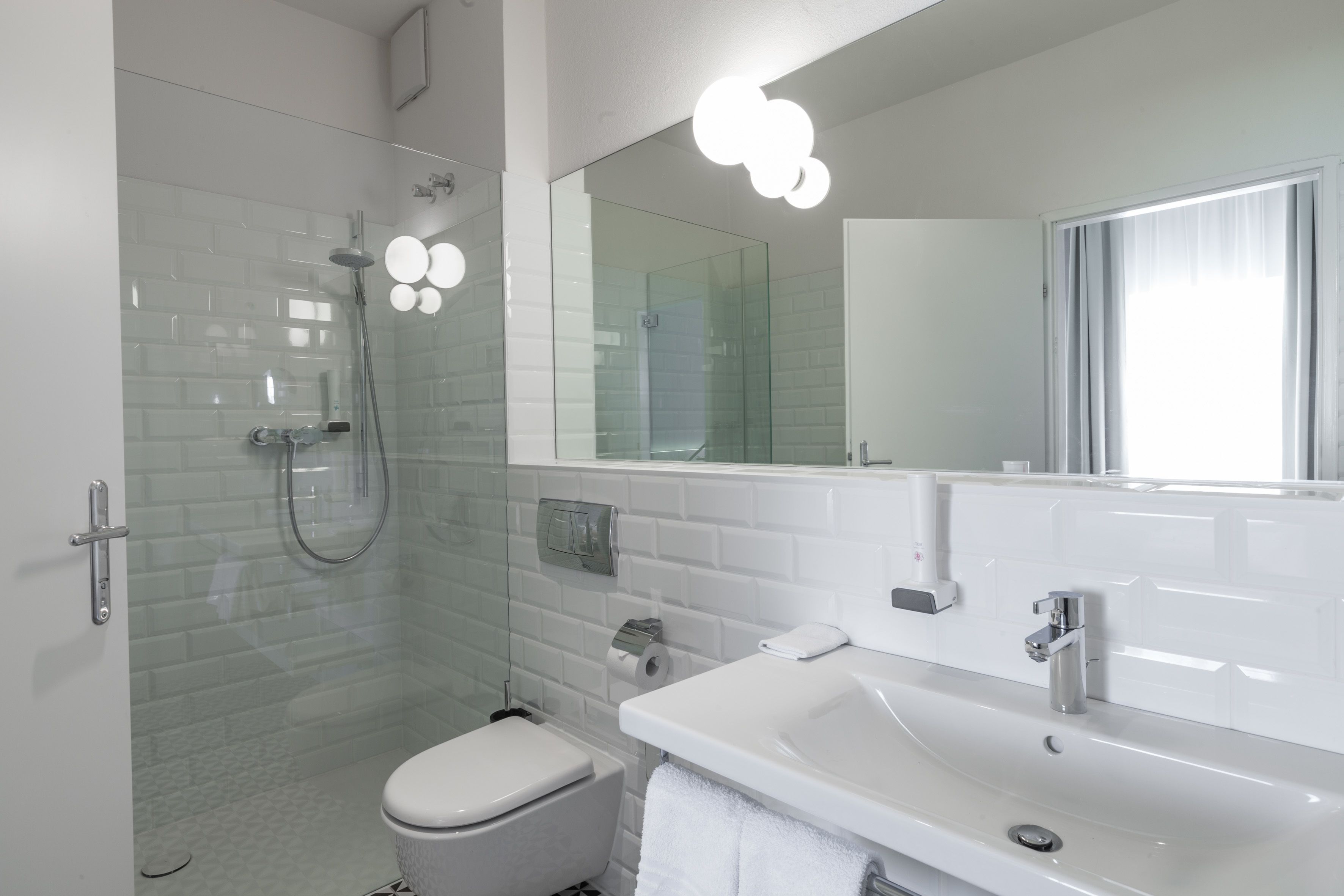 A modern bathroom with a glass shower enclosure, a white toilet, a sink with a mirror, and a towel rack.