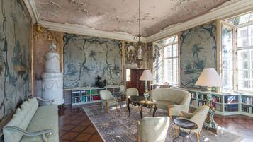Une vaste pièce dotée d’un plafond richement décoré, d’une grande fenêtre et d’un lustre classique.
