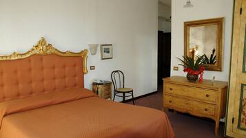 A bedroom with a large bed, a wooden dresser, a chair, and a mirror on the wall.