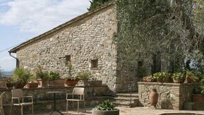 Edificio de piedra con un patio que incluye mobiliario de exterior y plantas en macetas.