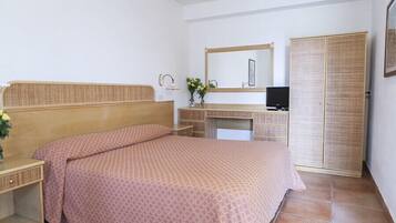 Ein Schlafzimmer mit einem Bett, einem Schreibtisch, einem Fernseher und einem Kleiderschrank.