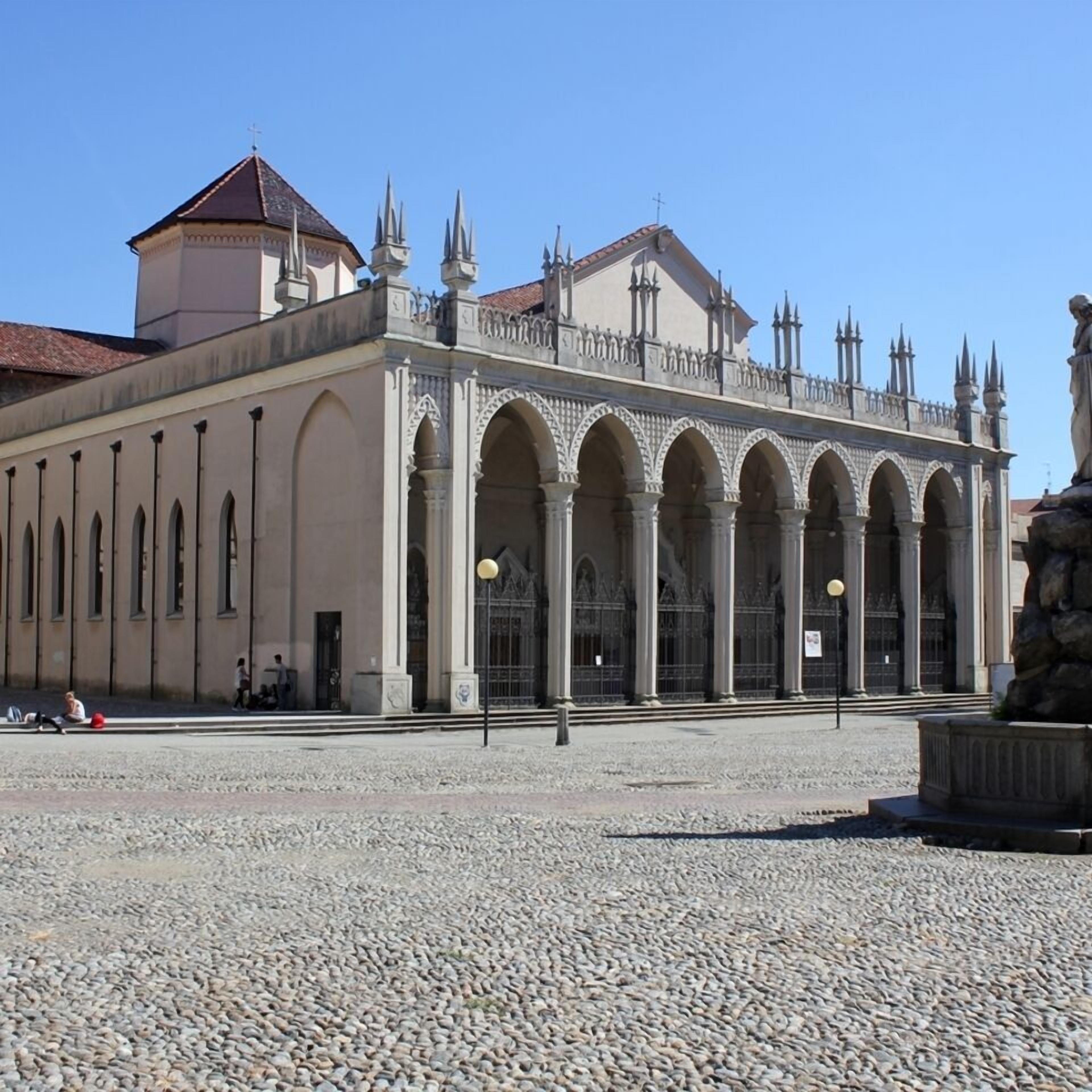 Ein historisches Gebäude mit einem zentralen Innenhof, das eine Reihe von Bögen und einen markanten Turm zeigt.