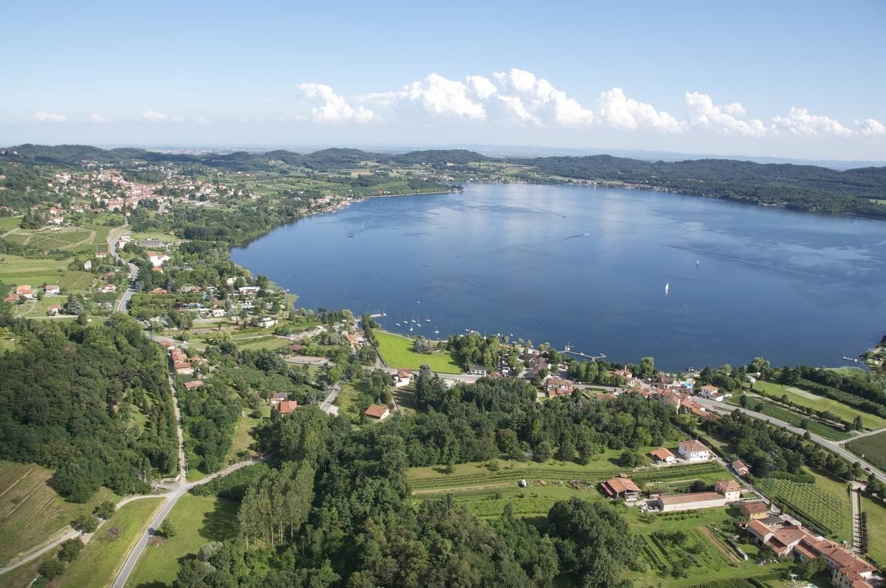 An aerial view of a lakeside town with residential areas, roads, and boats on the water.