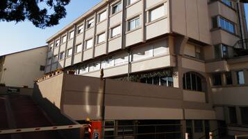 Um hotel de vários andares com fachada plana, janelas amplas e um sinal de estacionamento.
