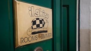 Une porte avec une pancarte indiquant « Chambres - Zimmer » et un symbole représentant un chapeau à carreaux.