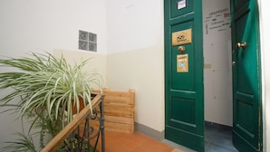 Une porte verte avec une plaque, un banc en bois et une plante en pot.