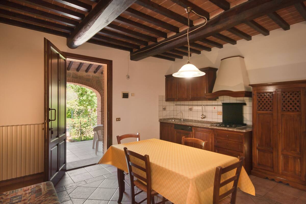 Une cuisine avec des meubles de rangement en bois, un pare-feu en carreaux et une table à manger avec des chaises.